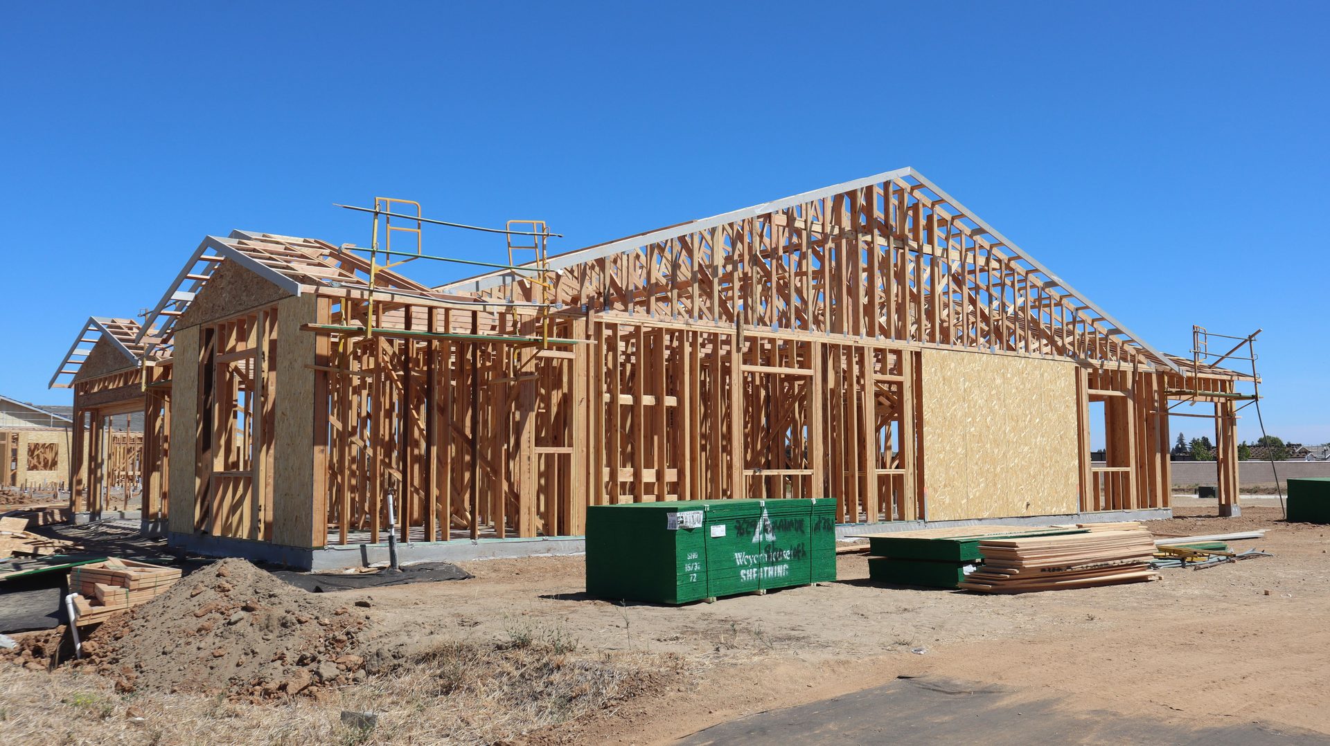 A timber house frame going up under a clear sky.